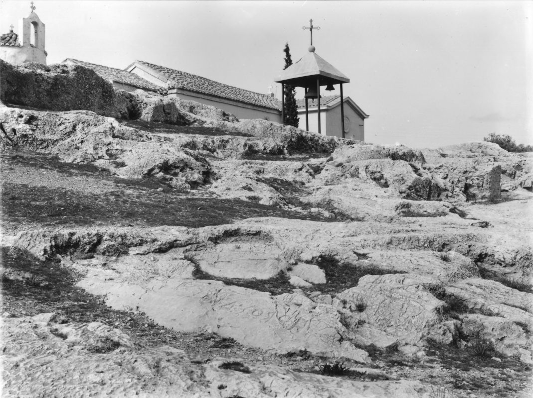 On the foreground, an outdoor Archaic shrine dedicated to Zeus is identified by the rupestral inscription (retrograde): HΟΡΟΣ ΔΙΟΣ (6th c. B.C.) (Nicholson Museum, Professor W.J. Woodhouse Collection).
